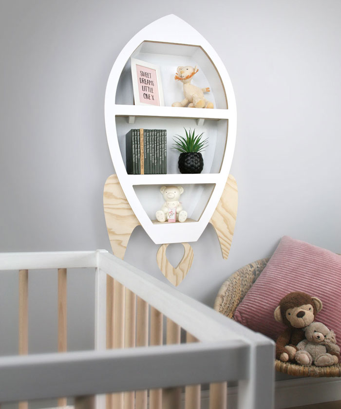 Rocket shaped nursery shelf in white wall mounted in babies nursery room setting.