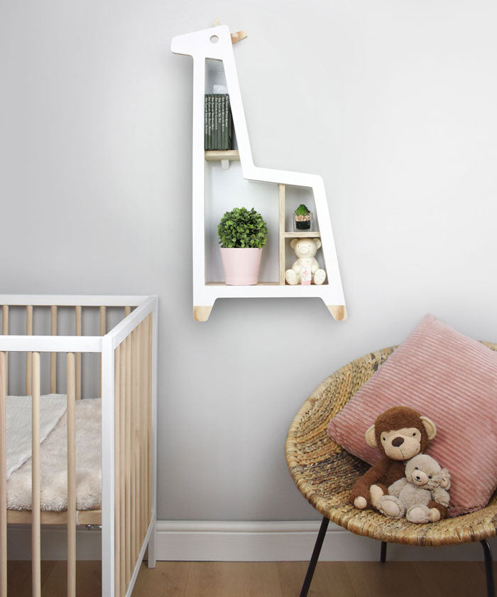 Giraffe shaped nursery shelf in white wall mounted in nursery room setting.