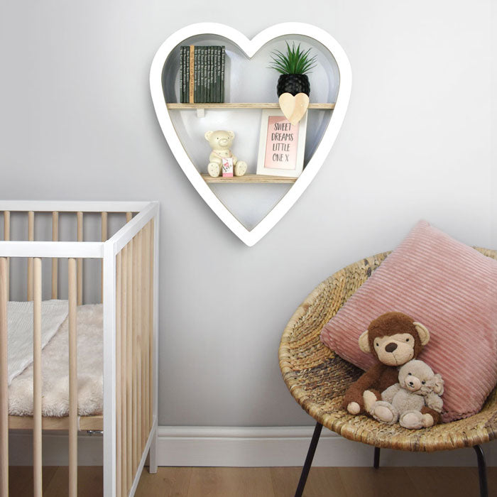 Heart shaped nursery shelf in white wall mounted in nursery room setting.