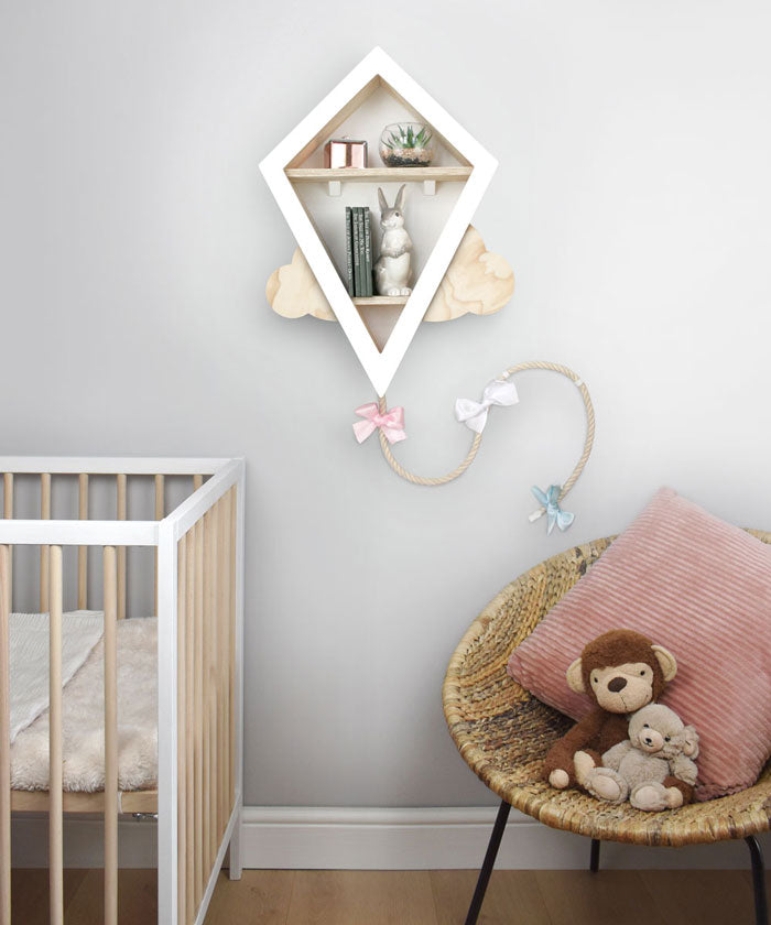 Kite shaped nursery shelf in white wall mounted in nursery room.