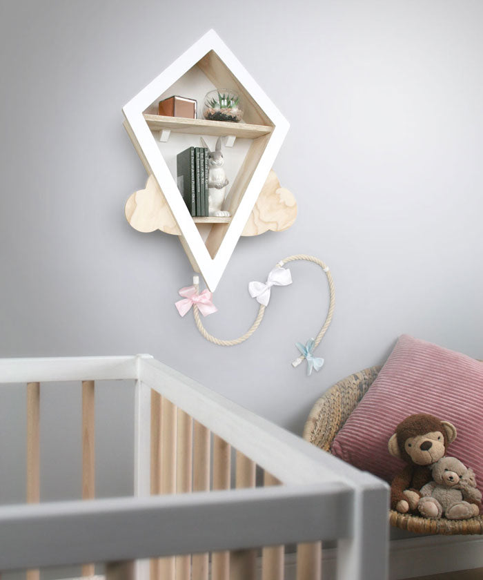 Kite shaped nursery shelf in white wall mounted in babies nursery setting.