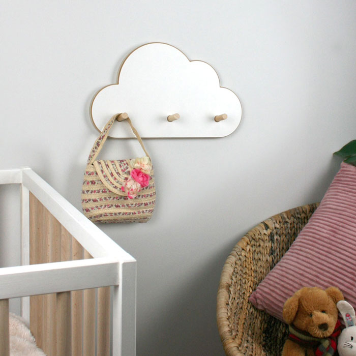 Cloud shaped peg hangers wall mounted in nursery setting.