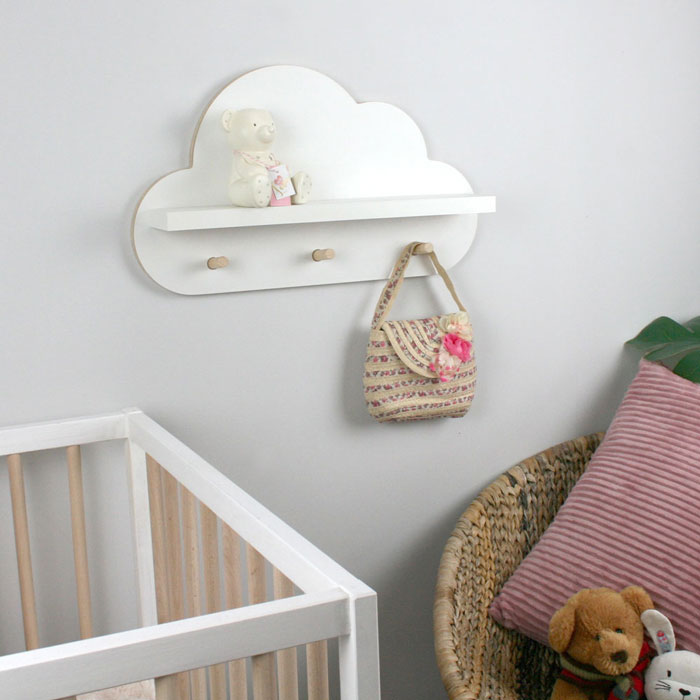 Cloud shaped nursery shelf in white with pegs hangers wall mounted in nursery room.