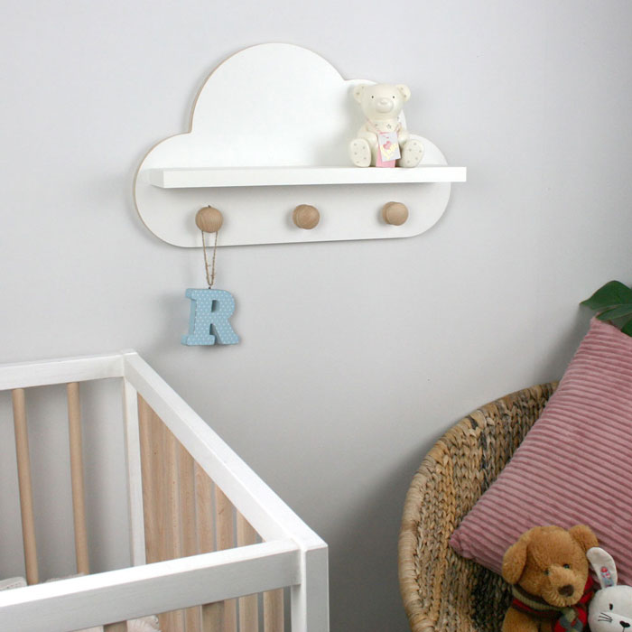 Cloud shaped nursery shelf in white with knob hangers wall mounted in nursery room.